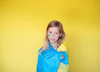 Portrait of smiling young woman against yellow background