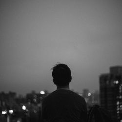 Rear view of man against illuminated cityscape