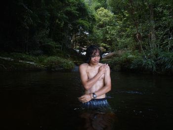 Shirtless man bathing in river at forest