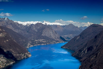 High angle view of lake and mountains against blue sky