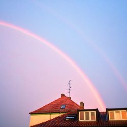 Low angle view of rainbow over house against sky