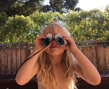 Close-up of topless girl using binoculars