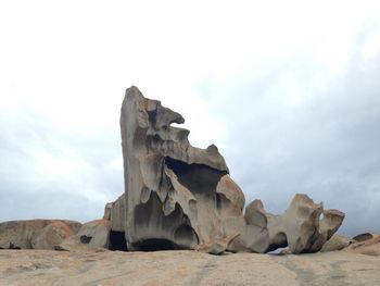 Low angle view of rocks against cloudy sky