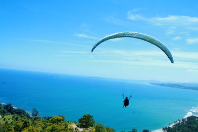 Man paragliding over sea against sky