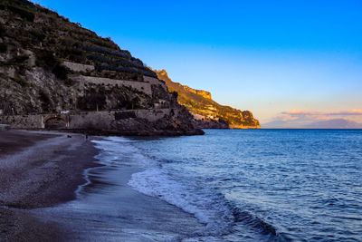 Scenic view of sea by cliff against blue sky