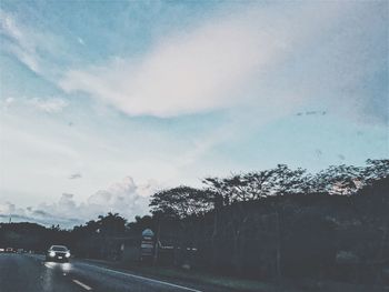 Road by trees against sky