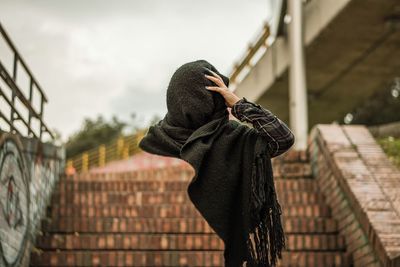 Digital composite image of woman wrapped in scarf on steps