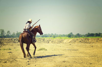 Person riding horse on field against sky