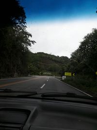 Road by trees against sky