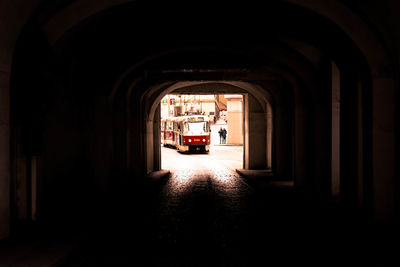 Tram moving on street seen through tunnel