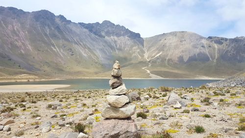 Statue on rock by landscape against sky