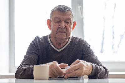 Portrait of elderly man. senior takes pills sitting at table