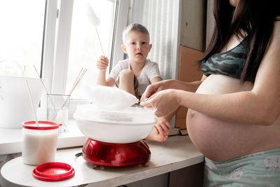 Pregnant woman with son preparing cotton candies at home