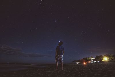 Rear view of man standing against sky at night