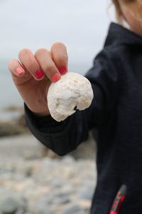 Midsection of girl holding seashell at beach