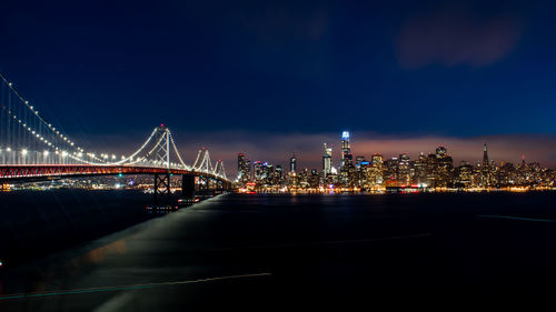 Illuminated bridge over river at night