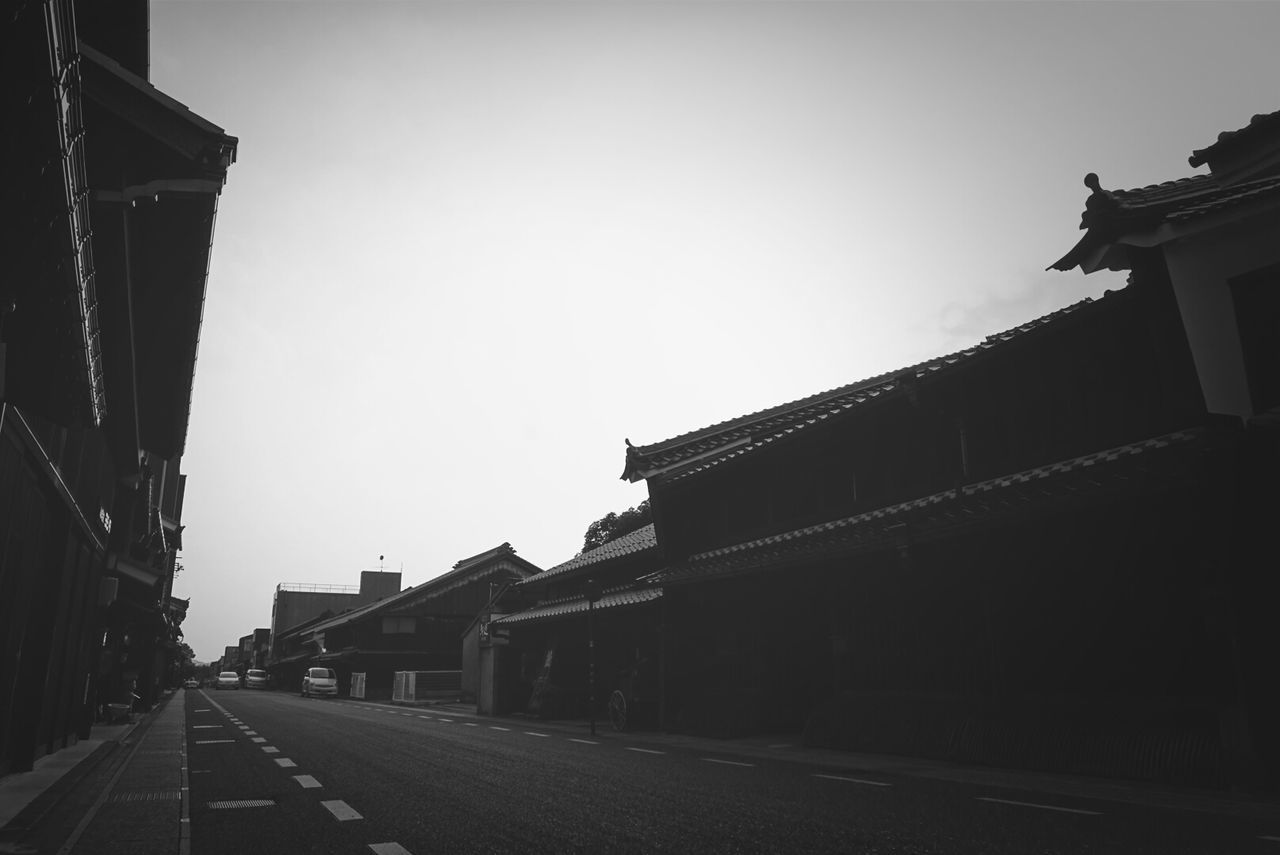 architecture, building exterior, built structure, the way forward, clear sky, street, road, sky, transportation, diminishing perspective, copy space, city, vanishing point, building, outdoors, no people, history, low angle view, road marking, day