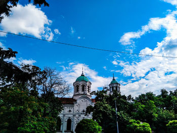 Low angle view of trees and building against sky