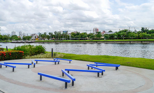 Scenic view of park by river in city against sky