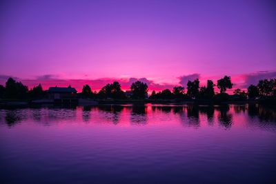 Silhouette trees by lake against sky during sunset