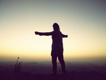 Full length of silhouette person standing on land against sky during sunset