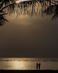 Silhouette people on beach against sky during sunset