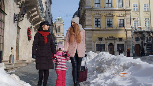 People on snow covered buildings during winter