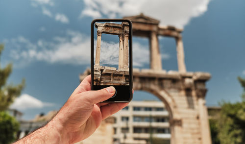 Man photographing through smart phone against sky