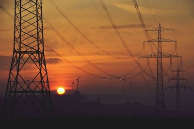 Silhouette electricity pylon against sky during sunset