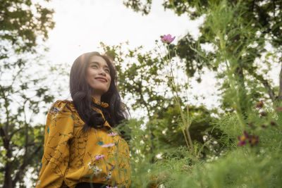 Low angle view of woman standing against tree