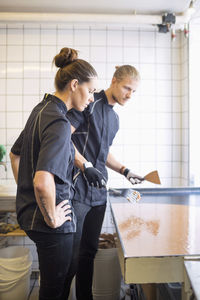 Workers looking at caramel in container at candy store