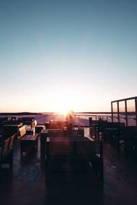 Silhouette people on bridge against clear sky during sunset