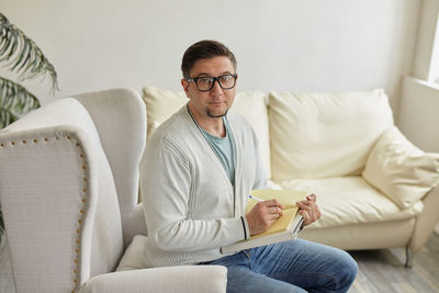 Portrait of smiling friends using digital tablet while sitting on sofa at home