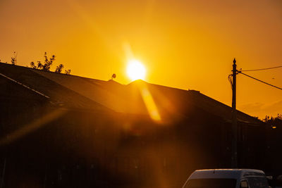 Silhouette car against orange sky during sunset