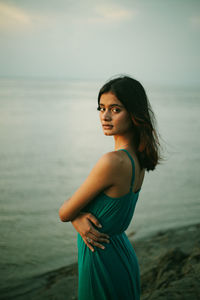 Portrait of young woman standing against the sea