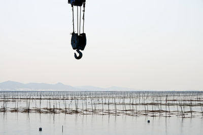 Crane pulley over sea against sky