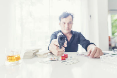 Businessman holding handgun while gambling at office desk