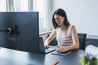 Smiling young graphic designer using laptop in office