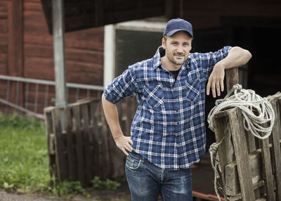 Portrait of confident farmer leaning on railing