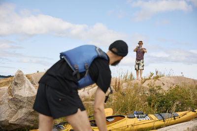 Men standing near kayaks at coast