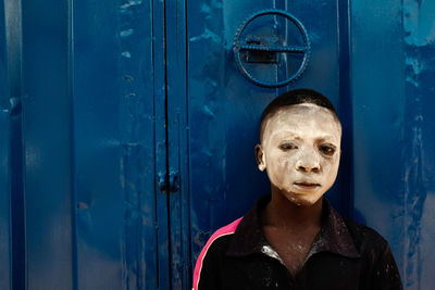 Portrait of man standing against blue door