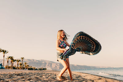 Beautiful woman standing on beach against sky