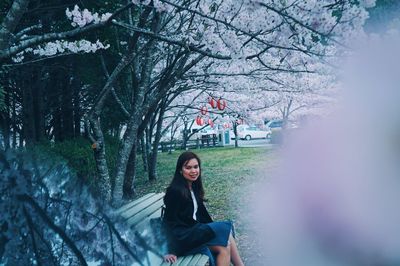 Portrait of woman standing by tree against plants