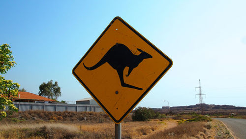 Road sign against clear blue sky