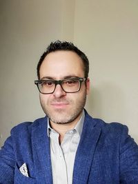 Portrait of man wearing eyeglasses against wall