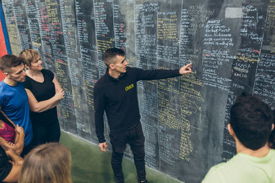 High angle view of instructor explaining over blackboard to athletes in gym