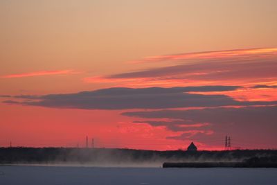 Silhouette factory against orange sky during sunset