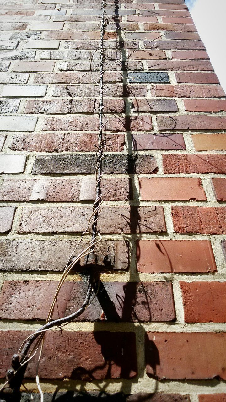 LOW ANGLE VIEW OF BRICK WALL WITH SHADOW ON TILED FLOOR