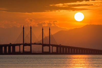 View of suspension bridge over sea during sunset