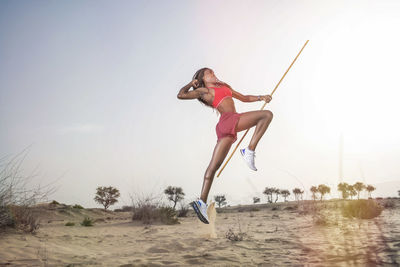 Full length of woman exercising in desert against sky